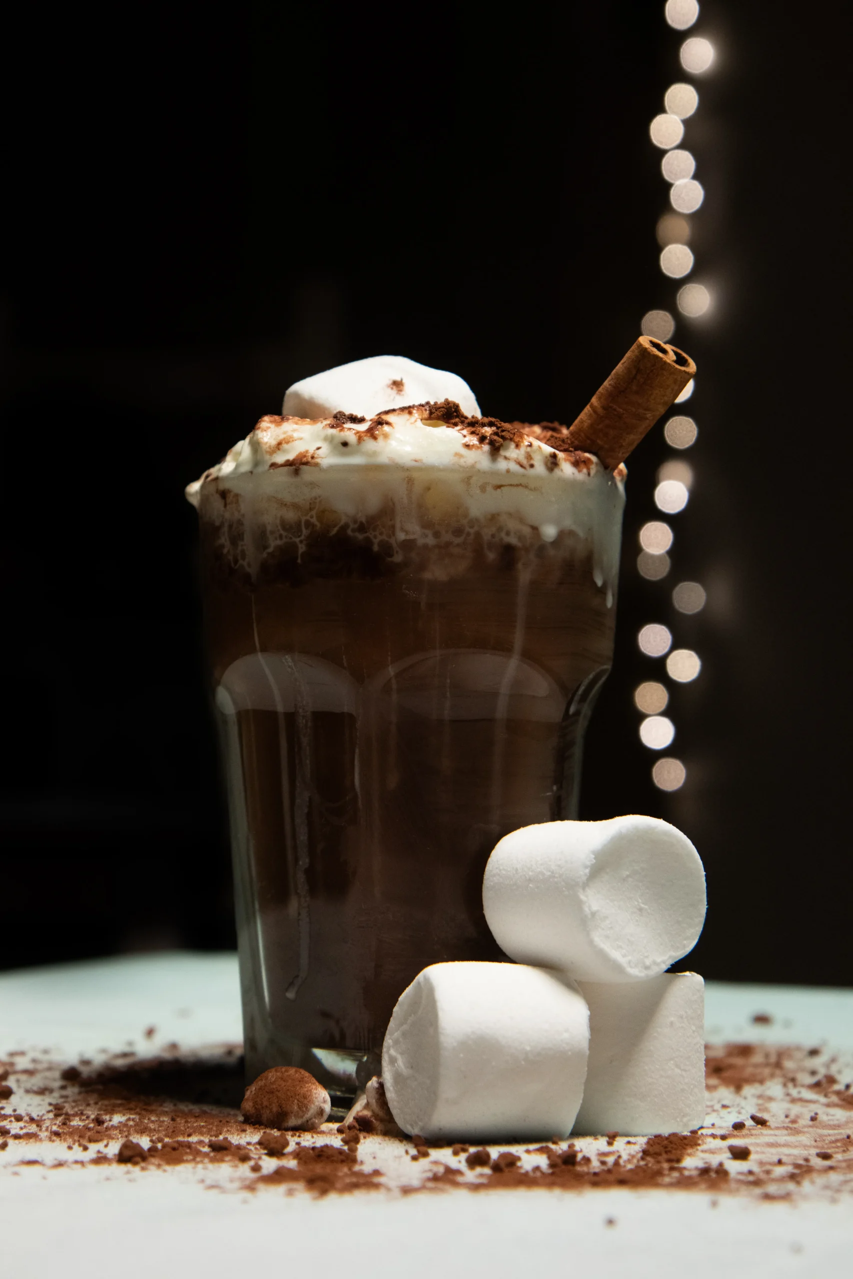 Warme chocomelk met marshmallows, slagroom, kaneel en bestrooid met cacao.